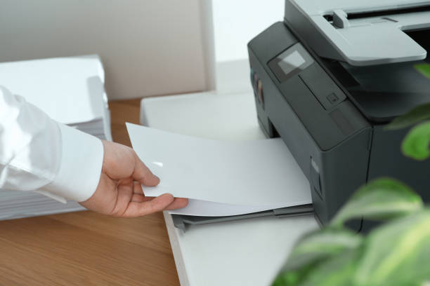 istock Woman loading paper into printer at wooden table indoors, closeup 1758414630