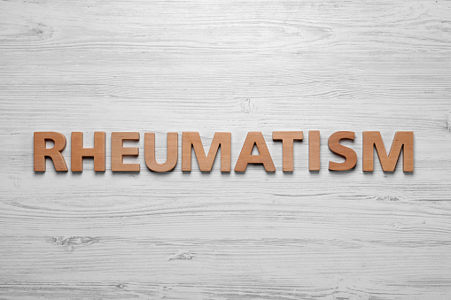Word Rheumatism made of letters on white wooden table, top view