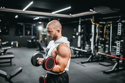 Young man training in gym with dumbbells