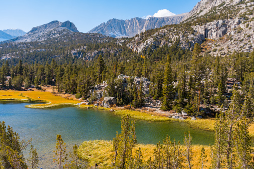 Hiking in Little Lakes Valley in the Eastern Sierra Nevada Mountains outside of Bishop, California. Alpine lakes, fall leaf colors, snow capped mountains and evergreen trees combine to make a picturesque scene.