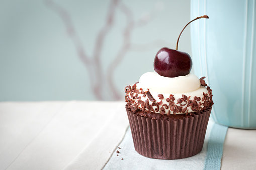 Black forest cupcake decorated with chocolate shavings and a single black cherry