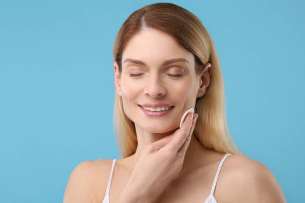 istock Beautiful woman removing makeup with cotton pad on light blue background 1758490231