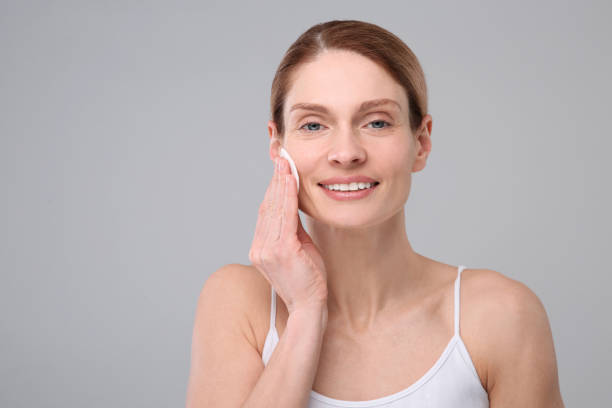 istock Beautiful woman removing makeup with cotton pad on gray background, space for text 1758490873