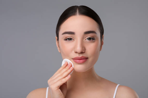 istock Beautiful woman removing makeup with cotton pad on gray background 1758513921