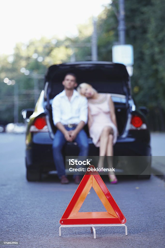 Emergency sign Young couple in a car with a red triangle in the foreground Adult Stock Photo