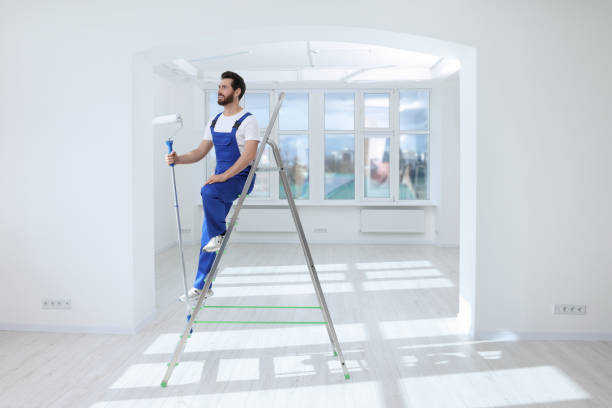 istock Handyman with roller on step ladder in room. Ceiling painting 1758532719