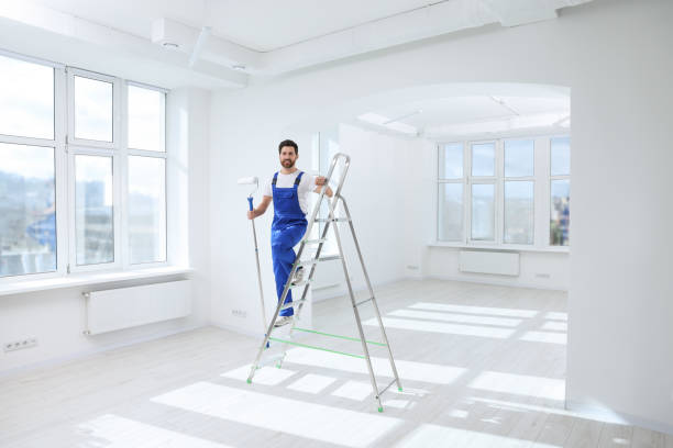 istock Handyman with roller on step ladder in room. Ceiling painting 1758532721