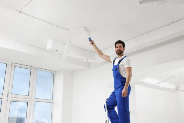 istock Handyman painting ceiling with roller on step ladder in room 1758533233