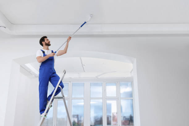 istock Handyman painting ceiling with roller on step ladder in room 1758533238