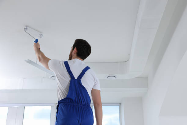 istock Handyman with roller painting ceiling in room, back view 1758533763