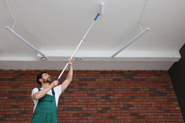 istock Handyman painting ceiling with roller in room, low angle view 1758533764