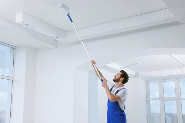 istock Handyman with roller painting ceiling in room 1758533765