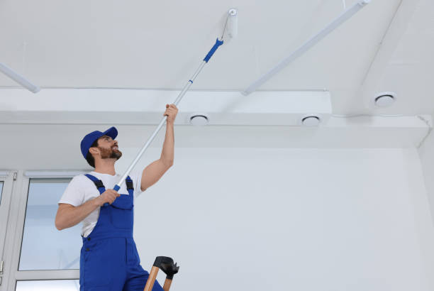 istock Handyman painting ceiling with roller on step ladder in room 1758533776