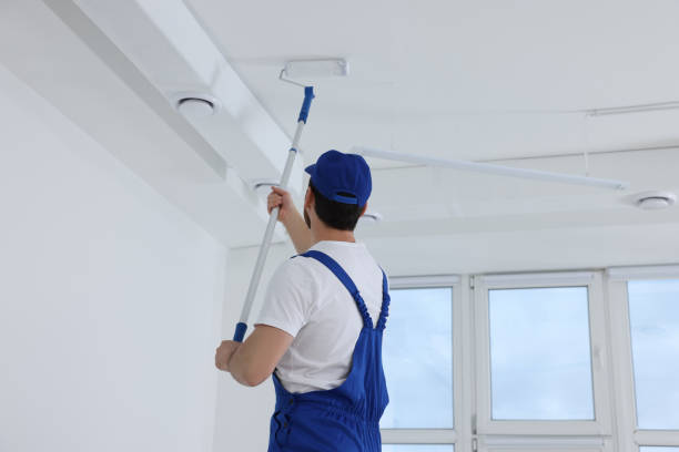 istock Handyman painting ceiling with roller in room, back view 1758534286