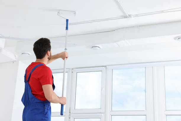 istock Handyman painting ceiling with roller in room, back view 1758534293