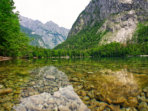 Landscape lakeshore view with crystal clear waters reflecting mountains around lake Obersee in Berchtesgaden national park, Bavaria, Germany