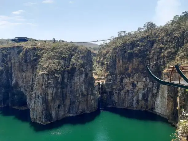 View of the Furnas dam canyon waterfall in Minas Gerais with a blue sky and suspension bridge above the waterfall