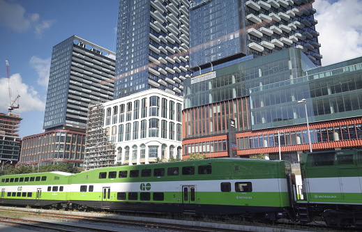 Toronto, Canada - August 28, 2023: Modern commercial and residential buildings line Front Street West in the Fashion District between Bathurst Street and Spadina Avenue. A GO 664 train heads east to nearby Union Station.