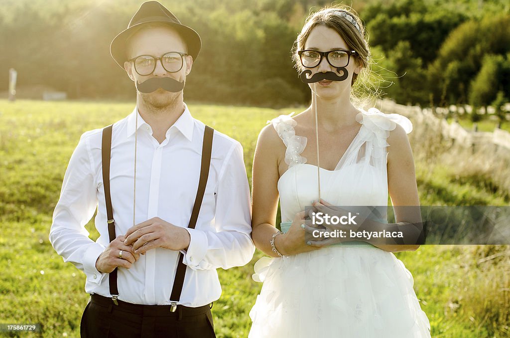 A newlywed couple poses with fake mustaches and glasses Vintage weddingHappy couple on wedding day. Bride and Groom. Vintage wedding. Couple - Relationship Stock Photo