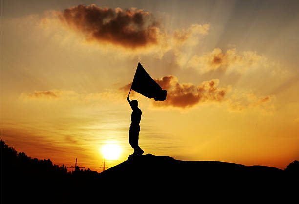 Silhouette of a man against dramatic sky tossing the caber - a traditional activity in Scottish Highland Games