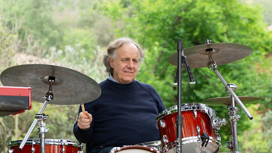 portrait of a senior drummer playing in the park