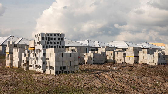 Stacks of concrete blocks partially obstruct a view of single-family houses under construction in a suburban development during a building boom in southwest Florida.