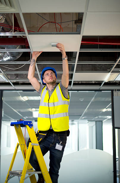 istock electrician fitting fire alarm to office interior 175869736