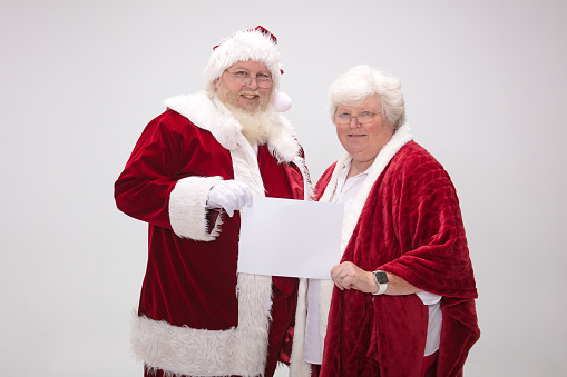 Mr. & Mrs. Santa Claus holding up a blank sign
