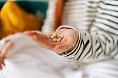 Close-up top view of unrecognizable young woman taking beauty supplements for glowing skin. Closeup of sick lady adding pills to heap of medicines.