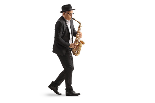 Full length profile shot of a mature male musician playing a sax isolated on white background