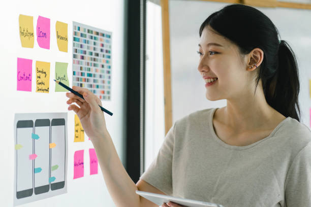 istock Creative UX UI designer working on screens for mobile responsive website development, focusing on UI UX. Developing wireframe sketch layout designs on a smartphone screen. 1758844824