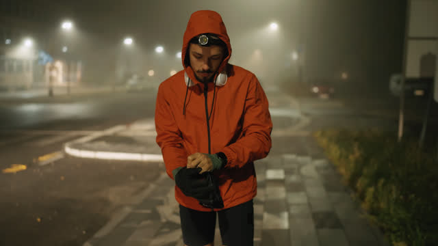 Young Athlete in Sportswear Putting On Winter Gloves on Sidewalk before Jogging in City at Night