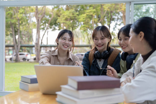 istock University students sitting together at table with book and laptop. Happy young people doing group study in college campus 1758921441