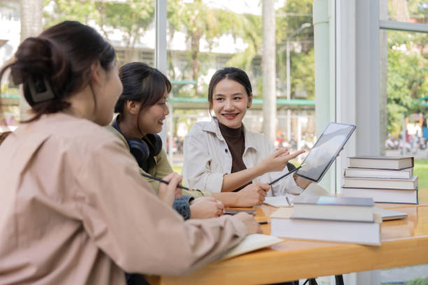 istock University students sitting together at table with book and laptop. Happy young people doing group study in college campus 1758921447