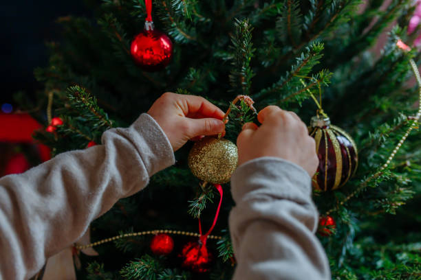 istock close up on child hands holding christmas tree decoration putting it on tree 1758980858