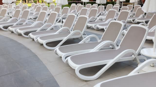 Stylish luxury sun lounger with reclining seats and closed umbrellas in luxury hotel resort