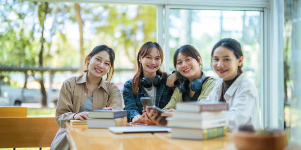 istock University students sitting together at table with book and laptop. Happy young people doing group study in college campus College and University life concept 1758992109