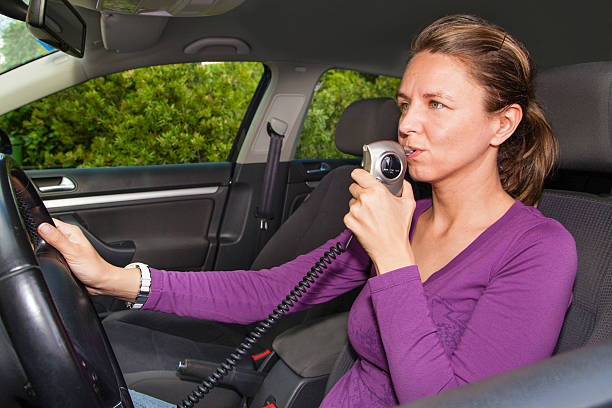 Woman in car blowing into breathalyzer