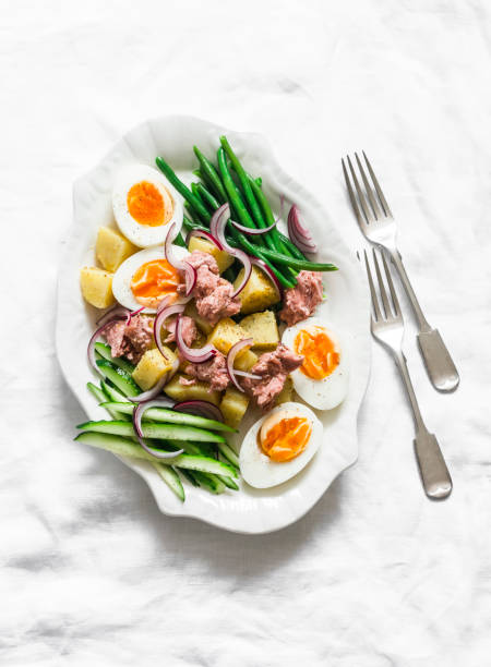 istock Breakfast plate - boiled eggs, potatoes, string beans, red onion, cucumber, canned tuna salad on a light background, top view 1759033359