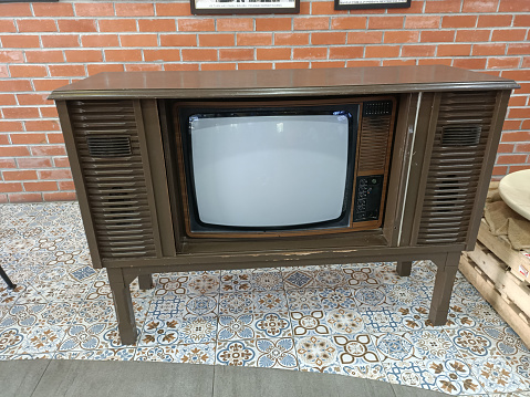 Vintage wooden TV set in a room with red brick wall background.photo taken in malaysia