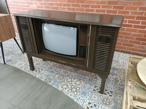 Vintage wooden TV set in a room with red brick wall background.photo taken in malaysia