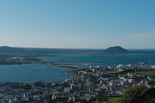 A scenic view of Jeju Island, South Korea, featuring a few buildings against the backdrop of the ocean