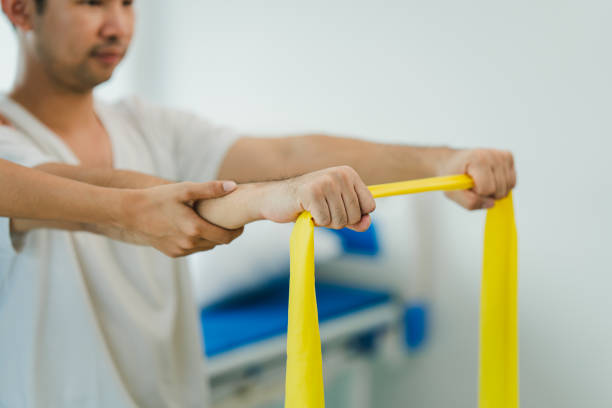 Physical therapist giving stretching exercises with elastic exercise bands and physical therapist hands helping male patient Physical therapy concept
