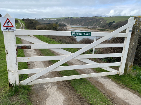 White gate entrance to a private road on a country lane