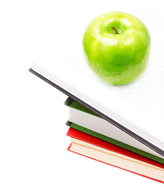 istock Open Book heap and green apple on top over white 175913560