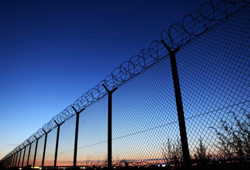 Barb wire fence at dusk - protection of Warsaw airport area (Poland).