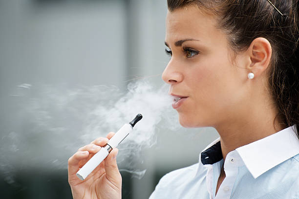 joven mujer fumando cigarrillo electrónico al edificio de oficinas - quit scene fotografías e imágenes de stock