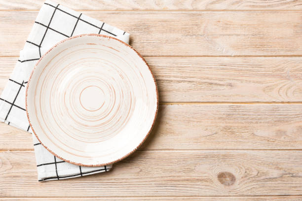 istock Top view on colored background empty round white plate on tablecloth for food. Empty dish on napkin with space for your design 1759142311