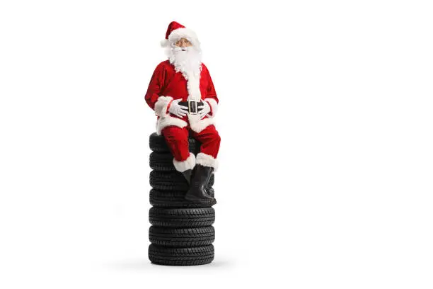 Santa claus sitting on a pile of vehicle tires isolated on white background