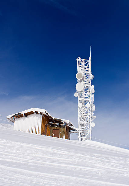 Beautiful winter rime frosting trees, communication tower and snowdrifts on mountain top on blue cloudy sky background (Carpathian mountain, Ukraine)
